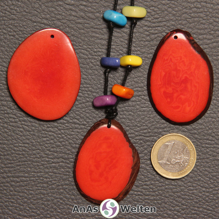 Drei rote Tagua-Nuss-Scheiben. Eine davon ist mit 6 Tagua-Nuss-Splittern in den Chakra-Farben als Kette gebunden.