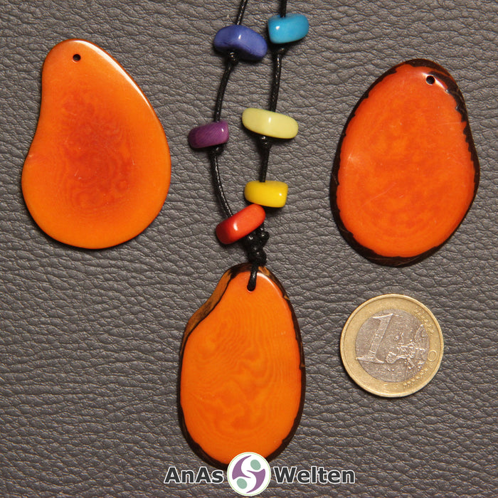 Drei orangene Tagua-Nuss-Scheiben. Eine davon ist mit 6 Tagua-Nuss-Splittern in den Chakra-Farben als Kette gebunden.