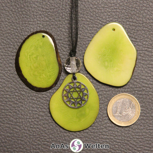 Drei grün gefärbte Tagua-Nuss-Scheiben. Eine davon ist als Kette mit Bergkristall und 4. Chakra Symbol gebunden.