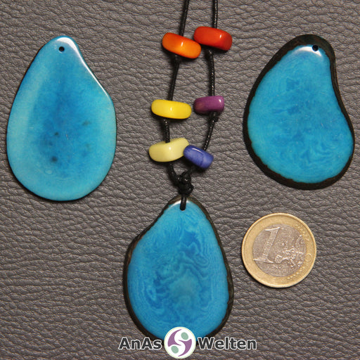 Drei türkise Tagua-Nuss-Scheiben. Eine davon ist mit 6 Tagua-Nuss-Splittern in den Chakra-Farben als Kette gebunden.