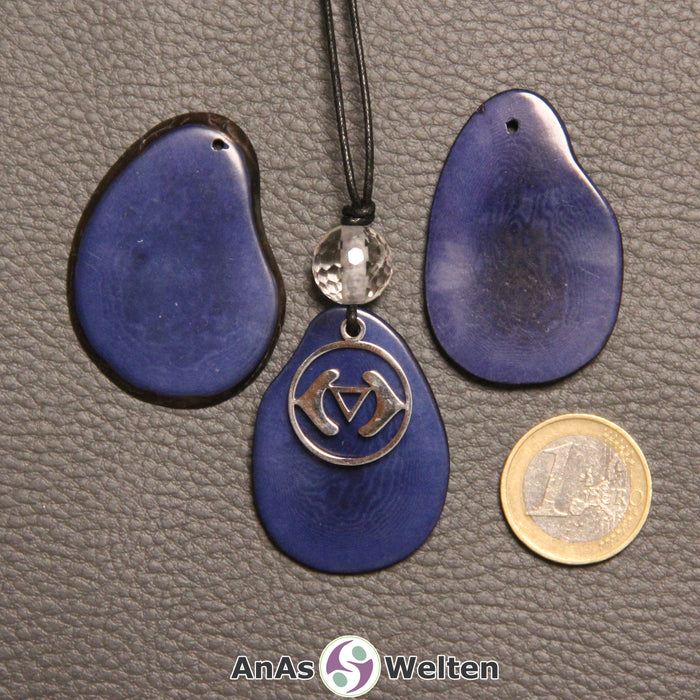 Drei blau gefärbte Tagua-Nuss-Scheiben. Eine davon ist als Kette mit Bergkristall und 6. Chakra Symbol gebunden.