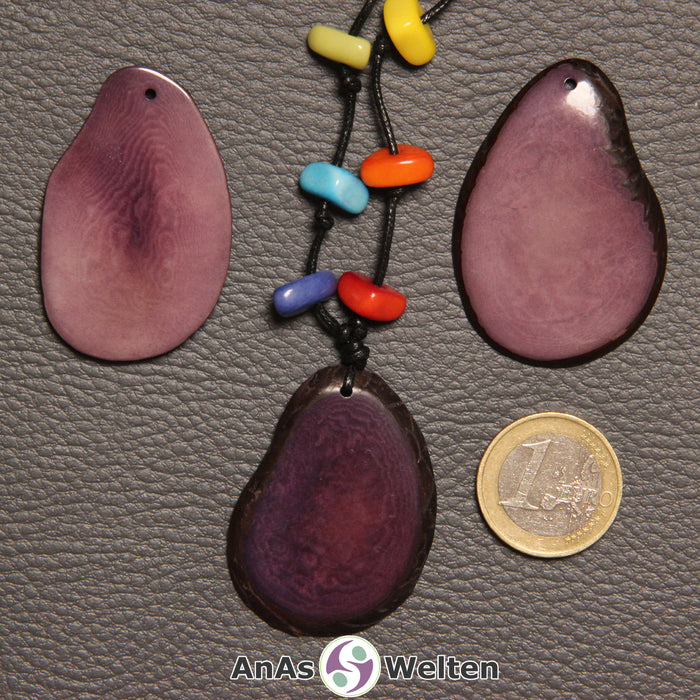 Drei lila Tagua-Nuss-Scheiben. Eine davon ist mit 6 Tagua-Nuss-Splittern in den Chakra-Farben als Kette gebunden.