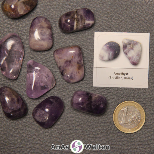 Mehrere Beispiele für den Amethyst Trommelstein. Daneben liegt der Sticker.