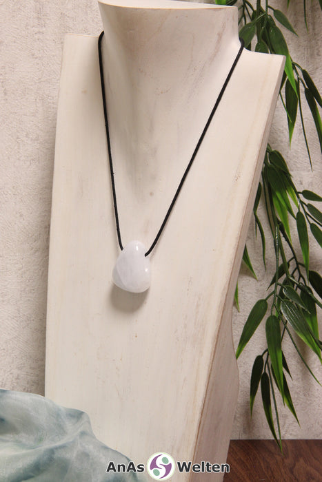 Ein Blauer Calcit gebohrter Trommelstein an einem schwarzen Baumwollband, der um eine helle Büste gehängt wurde.