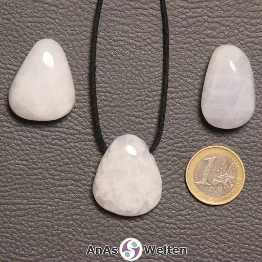 Drei Blauer Calcit gebohrte Trommelsteine nebeneinander. Einer befindet sich an einem schwarzen gewachsten Baumwollband.