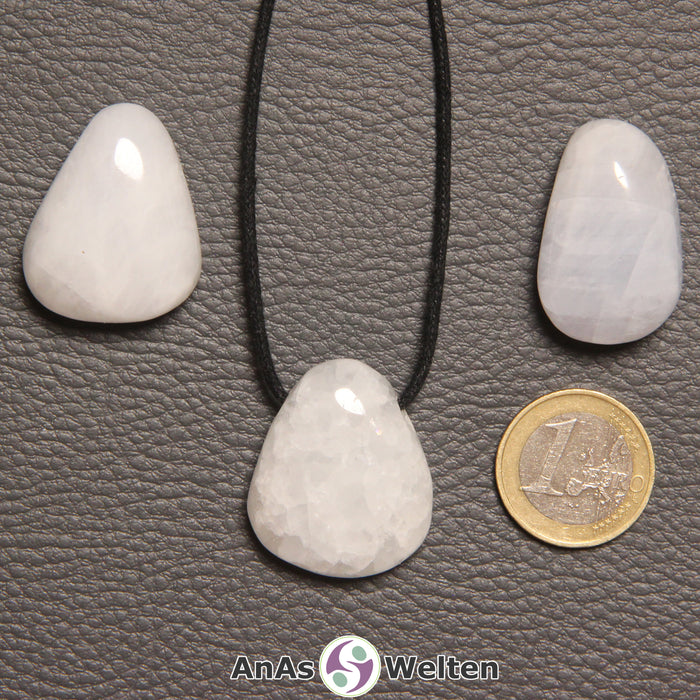 Drei Blauer Calcit gebohrte Trommelsteine nebeneinander. Einer befindet sich an einem schwarzen gewachsten Baumwollband.