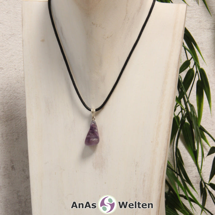 Ein lila Charoit Stein mit Öse an einem schwarzen Baumwollband, der um eine helle Büste gehängt wurde.