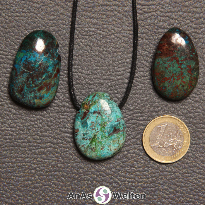 Drei blau-grün-braune Chrysokoll gebohrte Trommelsteine nebeneinander. Einer befindet sich an einem schwarzen gewachsten Baumwollband.
