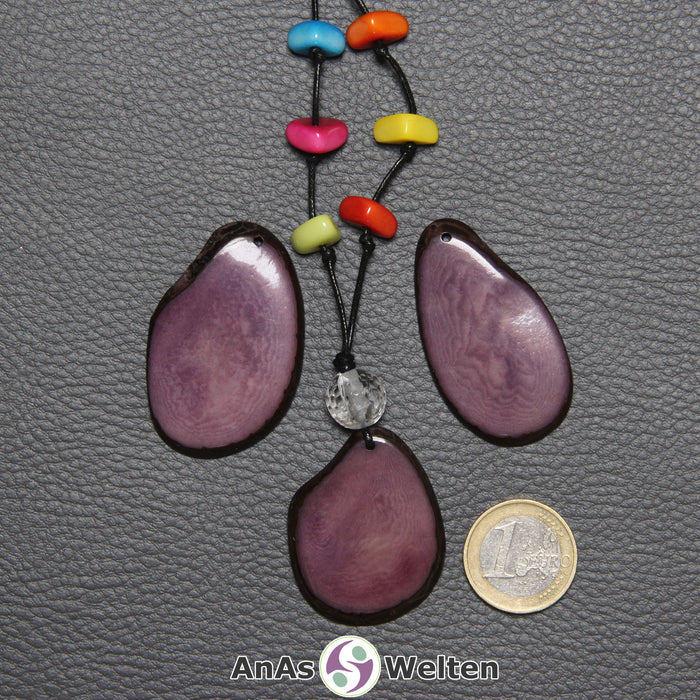 Drei lila Tagua-Nuss-Scheiben. Eine ist mit einer Bergkristallkugel und 6 bunten Tagua-Splittern als Kette gebunden.
