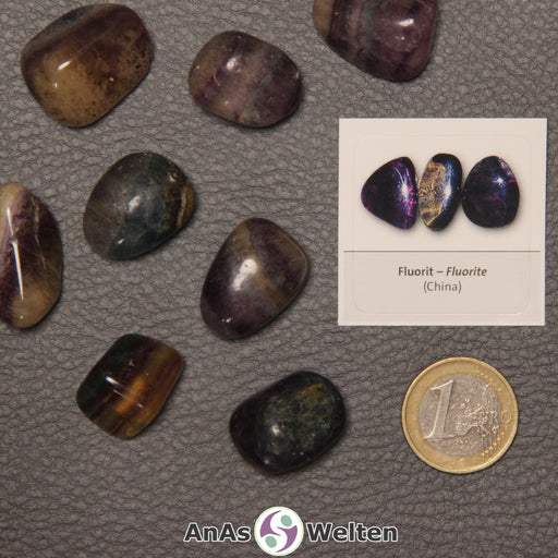 Mehrere Beispiele für den Fluorit Trommelstein. Daneben liegt der Sticker.