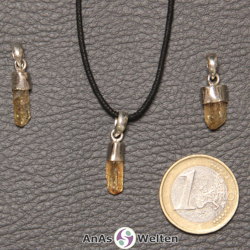 Drei gelbe Goldtopas Steine mit Öse nebeneinander. Einer befindet sich an einem schwarzen gewachsten Baumwollband.