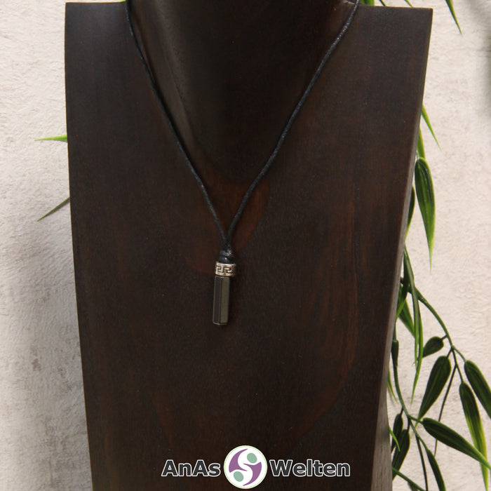 Eine dunkelgraue Hämatin Stift-Anhänger klein Kette mit einem Metallelement über dem Edelstein an einer hellen Büste.