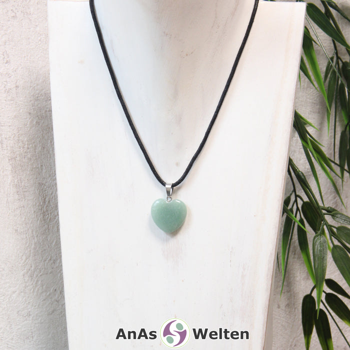 Ein Aventurin Herz Anhänger an einem schwarzen Baumwollband, der um eine helle Büste gehängt wurde.