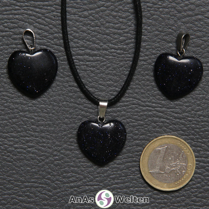 Drei Herzanhänger aus Blaufluss nebeneinander. Einer befindet sich an einem schwarzen gewachsten Baumwollband.