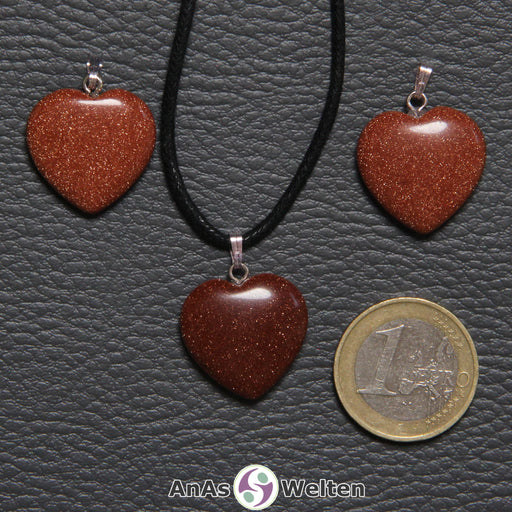 Drei Herzanhänger aus Goldfluss nebeneinander. Einer befindet sich an einem schwarzen gewachsten Baumwollband.