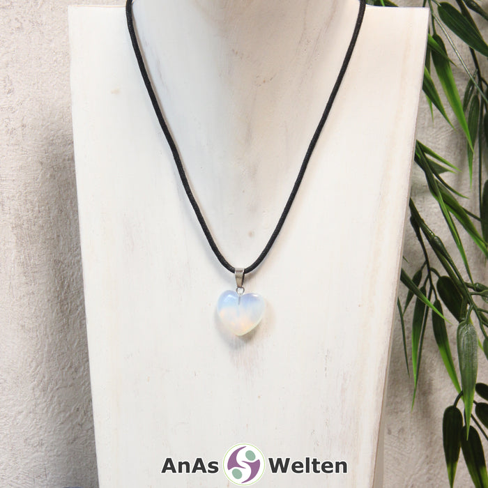 Ein Opalglas Herz Anhänger an einem schwarzen Baumwollband, der um eine helle Büste gehängt wurde.