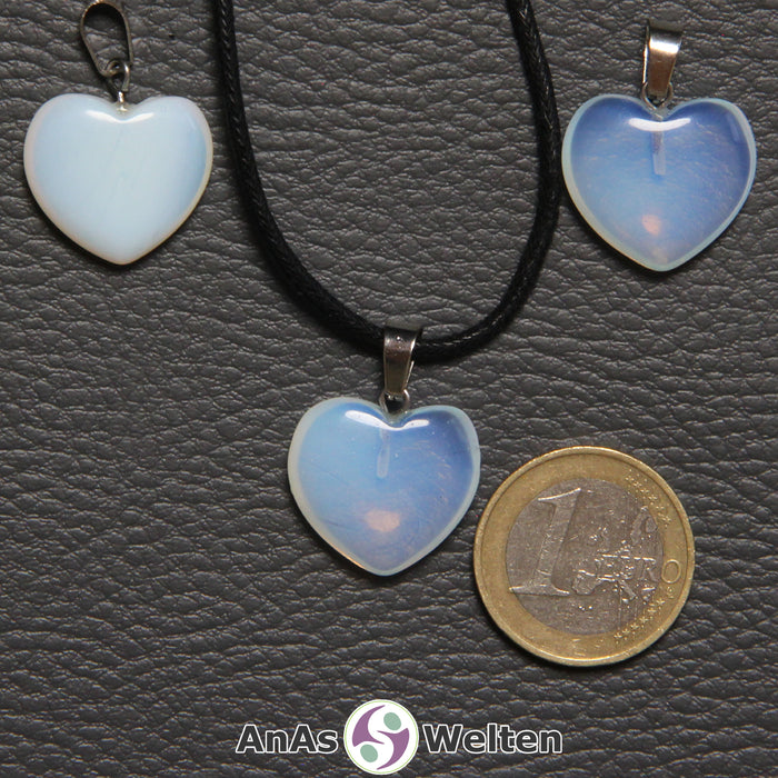 Drei Herzanhänger aus Opalglas nebeneinander. Einer befindet sich an einem schwarzen gewachsten Baumwollband.
