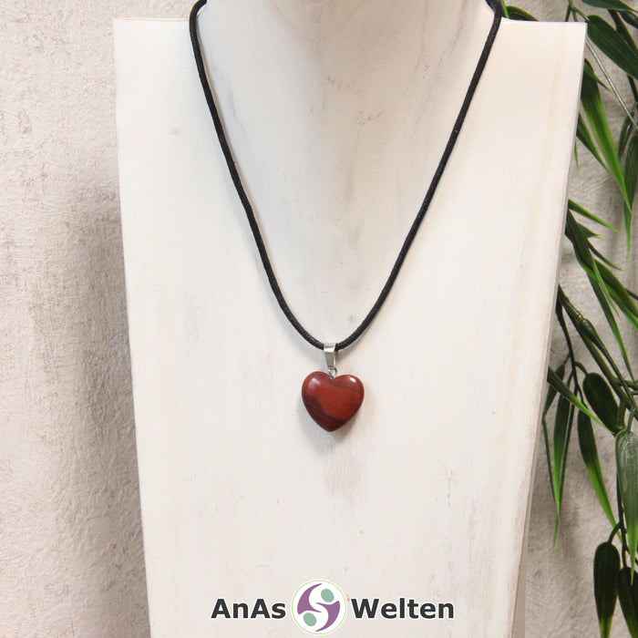 Ein Roter Jaspis Herz Anhänger an einem schwarzen Baumwollband, der um eine helle Büste gehängt wurde.