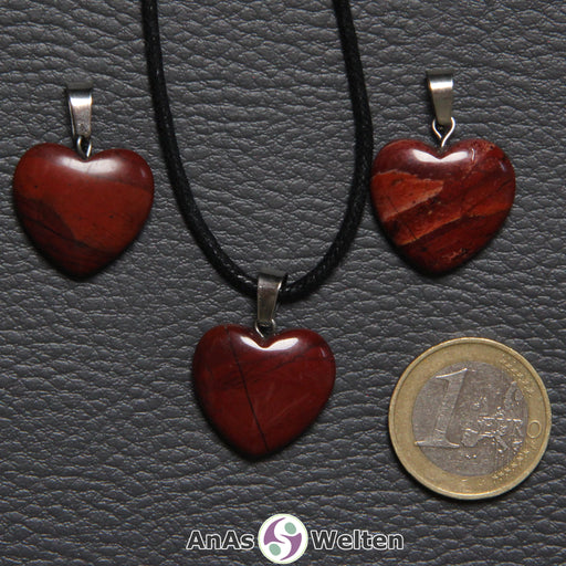 Drei Herzanhänger aus Rotem Jaspis nebeneinander. Einer befindet sich an einem schwarzen gewachsten Baumwollband.