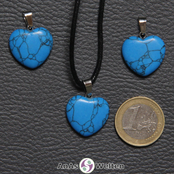 Drei Herzanhänger aus Turquenit nebeneinander. Einer befindet sich an einem schwarzen gewachsten Baumwollband.