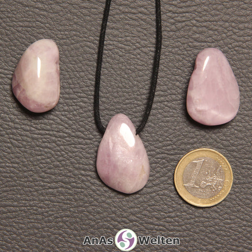 Drei rosa Kunzit gebohrte Trommelsteine nebeneinander. Einer befindet sich an einem schwarzen gewachsten Baumwollband.