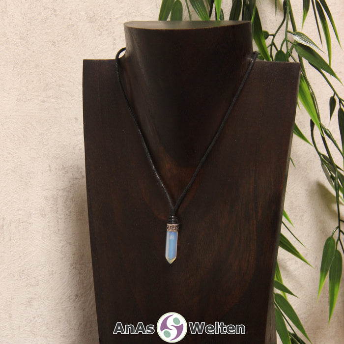 Das Bild zeigt einen Opalglas Stift-Anhänger klein mit Kette. Der Stift-Anhänger ist halbdurchsichtig und schimmert je nach Lichteinfall in einer weißen, blauen und/oder roten Farbe schimmert. Am oberen Ende verbindet ein silberfarbenes Element den Edelstein mit der Stoffkordel.