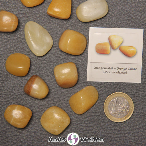 Mehrere Beispiele für den Orangencalcit Trommelstein. Daneben liegt der Sticker.
