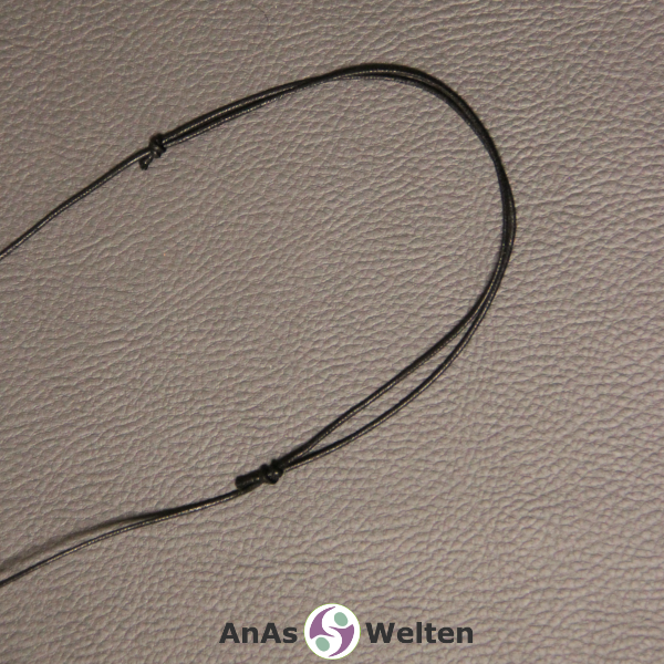 Ein schwarzes Baumwollband mit 1 mm Dicke, bei dem man den Schiebeknoten sieht, mit dem es zur Kette gebunden wurde.