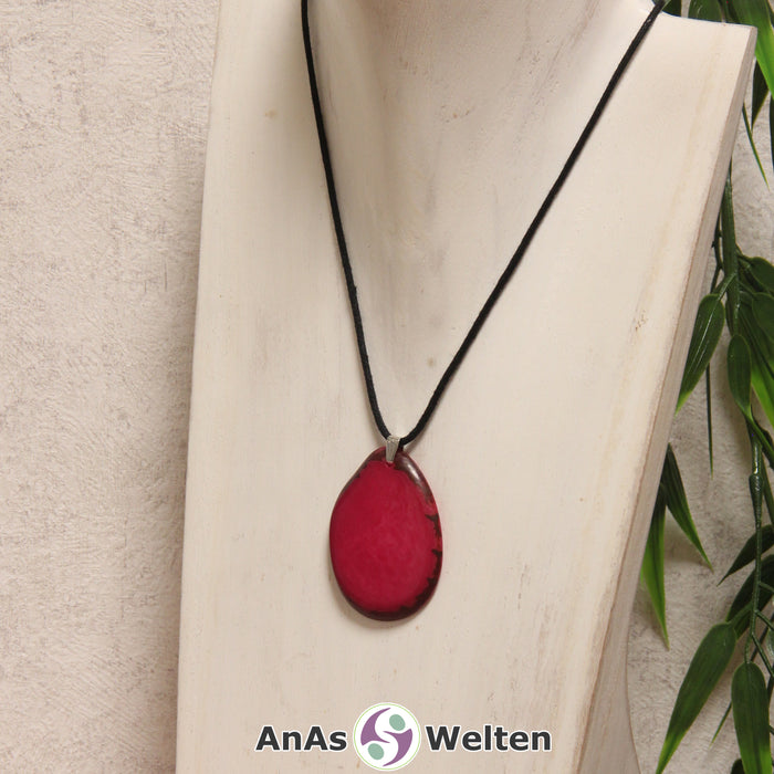 Eine fuchsiafarbene Tagua-Nuss Schmuck Kette mit Öse mit einem schwarzen Baumwollband an einer hellen Büste.