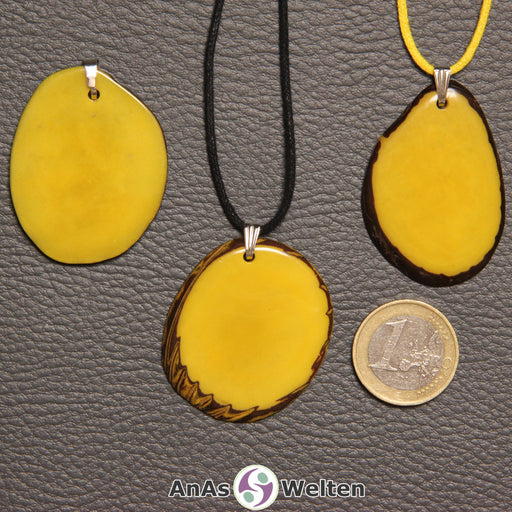 Drei gelb gefärbte Tagua-Nuss-Scheiben mit Metallöse. Zwei sind an einem schwarzen bzw. gelben Baumwollband.