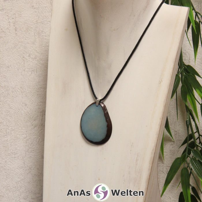 Eine himmelblaue Tagua-Nuss Schmuck Kette mit Öse mit einem schwarzen Baumwollband an einer hellen Büste.