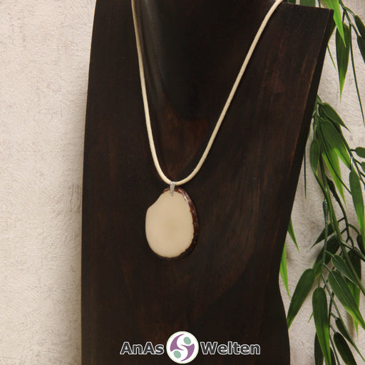 Das Produktbild zeigt die Tagua-Nuss-Schmuck Kette himmlblau. Zu sehen ist eine hellblaue Tagua-Nuss-Scheibe, die mit einer Edelstahlöse an einem beigen Baumwollband befestigt ist. Die Nuss-Scheibe hat einen dunklen Rand und eine glänzende Oberfläche.