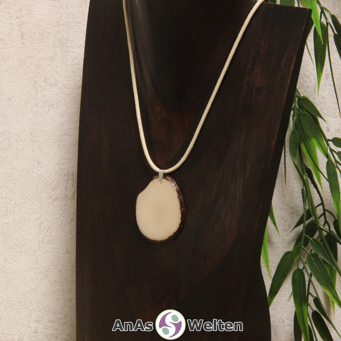 Das Produktbild zeigt die Tagua-Nuss-Schmuck Kette himmlblau. Zu sehen ist eine hellblaue Tagua-Nuss-Scheibe, die mit einer Edelstahlöse an einem beigen Baumwollband befestigt ist. Die Nuss-Scheibe hat einen dunklen Rand und eine glänzende Oberfläche.