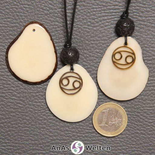 Drei Tagua-Nuss-Scheiben in naturfarben. Zwei davon sind als Kette mit Lavakugel und Krebs-Symbol gebunden.
