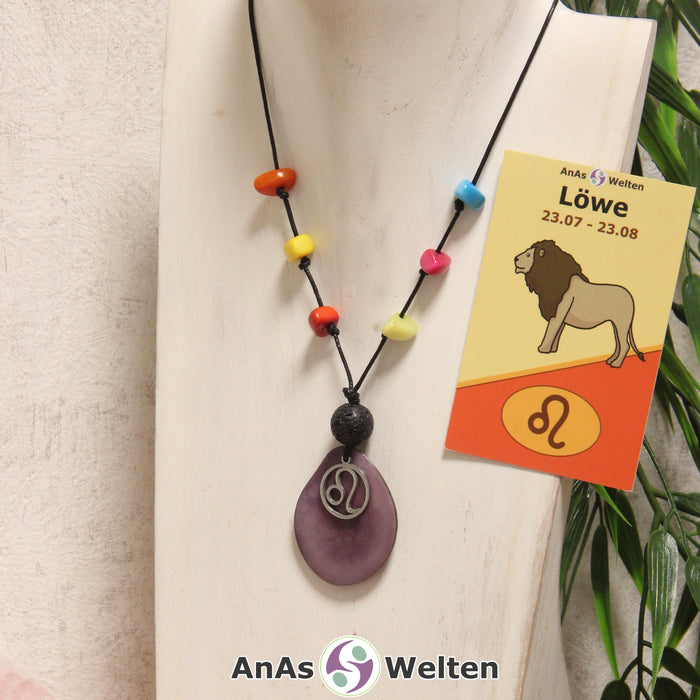 Eine lila Tagua-Nuss Sternzeichen Kette mit bunten Taguasplittern, silber Löwe-Symbol und Lavakugel an einer hellen Büste.