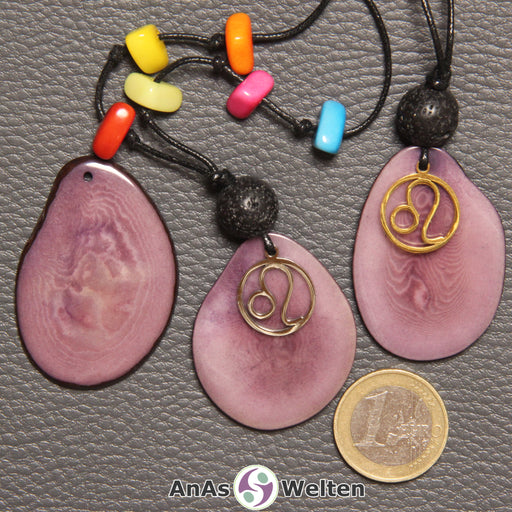 Drei lila Tagua-Nuss-Scheiben. Zwei davon sind als Kette mit Lavakugel, bunten Tagua-Splittern und Löwe-Symbol gebunden.