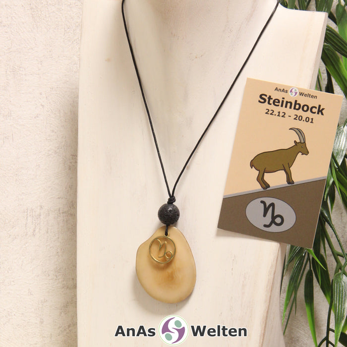 Eine beige gefärbte Tagua-Nuss Sternzeichen Kette mit goldfarbenem Steinbock-Symbol und Lavakugel an einer hellen Büste.