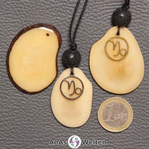 Drei Tagua-Nuss-Scheiben in beige. Zwei davon sind als Kette mit Lavakugel und Steinbock-Symbol gebunden.