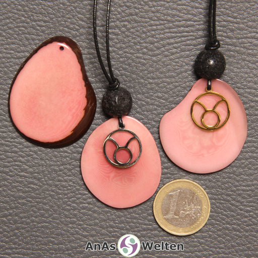 Drei Tagua-Nuss-Scheiben in rosa. Zwei davon sind als Kette mit Lavakugel und Stier-Symbol gebunden.
