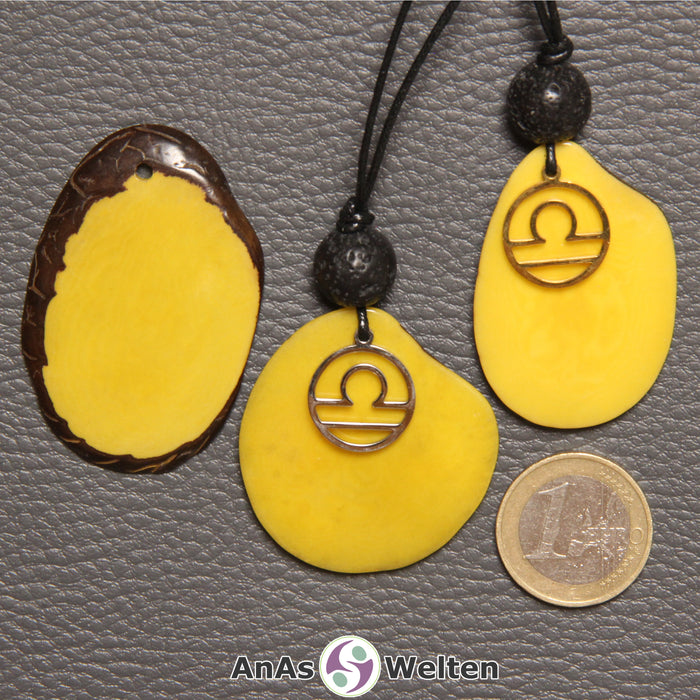 Drei Tagua-Nuss-Scheiben in gelb. Zwei davon sind als Kette mit Lavakugel und Waage-Symbol gebunden.
