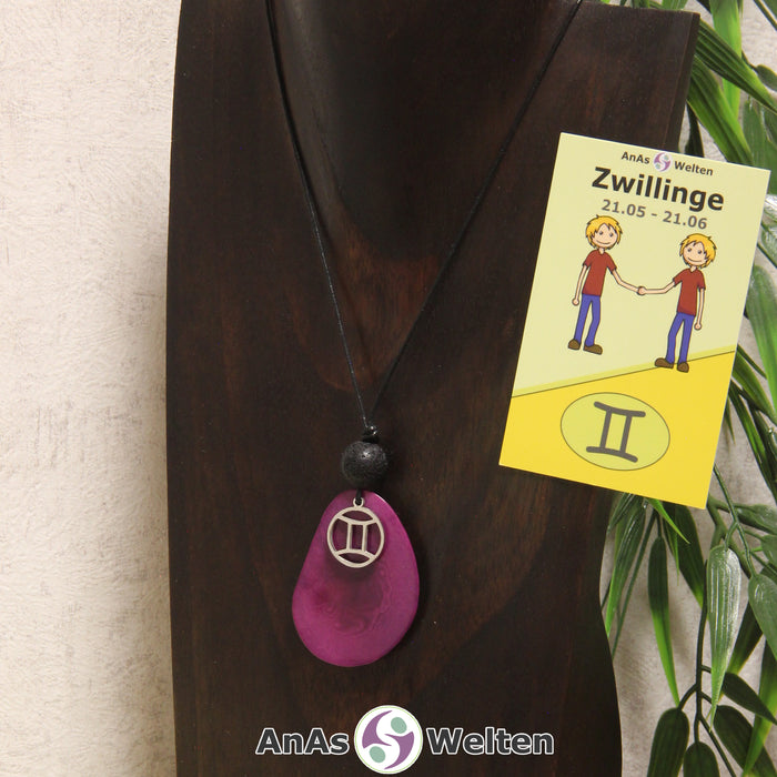 Eine violett gefärbte Tagua-Nuss Sternzeichen Kette mit silberfarbenem Zwillinge-Symbol und Lavakugel an einer dunklen Büste.