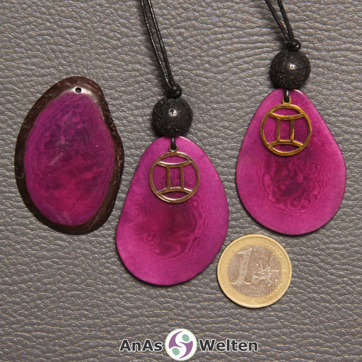 Drei Tagua-Nuss-Scheiben in violett. Zwei davon sind als Kette mit Lavakugel und Zwillinge-Symbol gebunden.