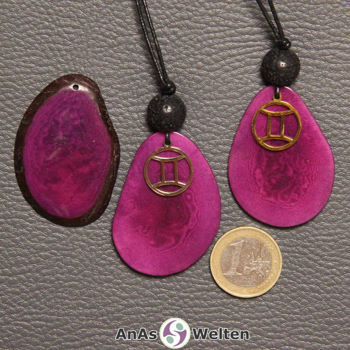 Drei Tagua-Nuss-Scheiben in violett. Zwei davon sind als Kette mit Lavakugel und Zwillinge-Symbol gebunden.