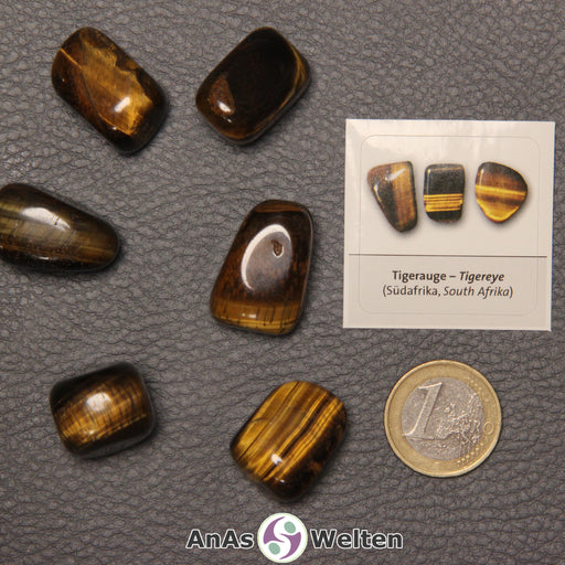Mehrere Beispiele für den Tigerauge Trommelstein. Daneben liegt der Sticker.