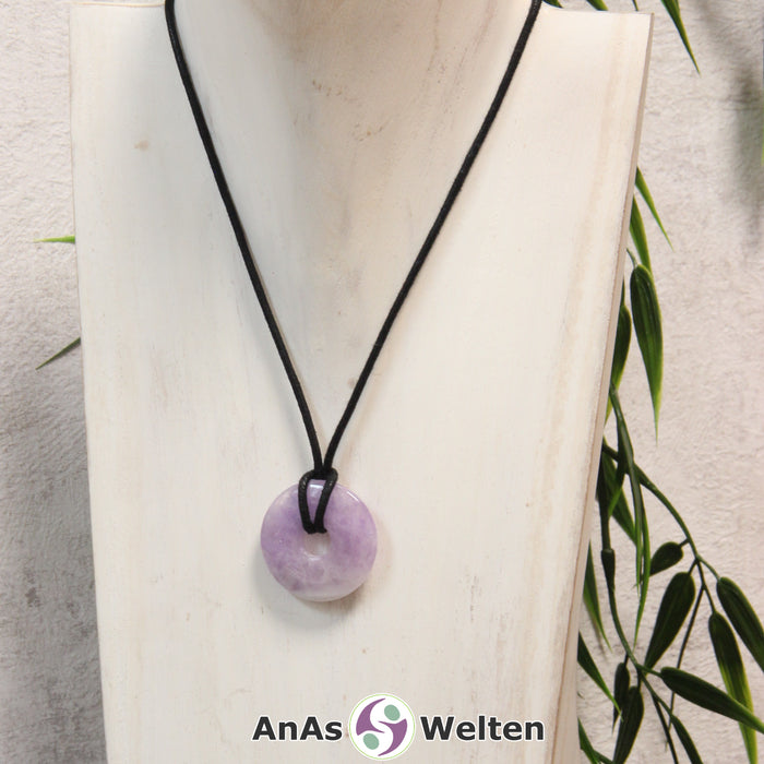 Ein Amethyst Donut als Kette an einem schwarzen gewachsten Baumwollband um eine helle Büste.