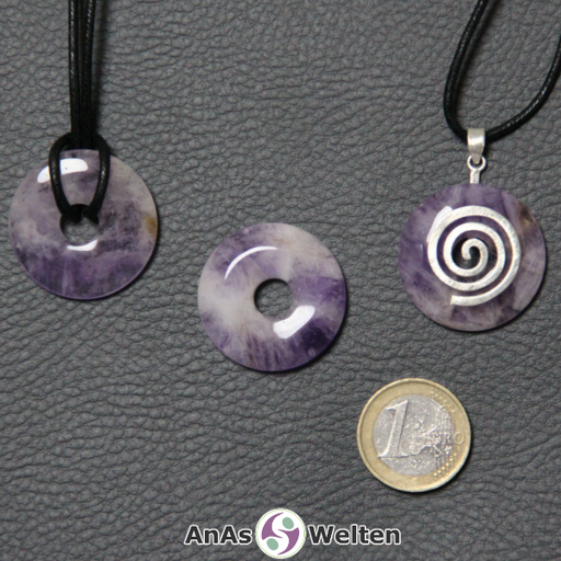 Drei Amethyst Donuts nebeneinander. Einer an einem Baumwollband, ein anderer an einem Donut-Halter mit Baumwollband.