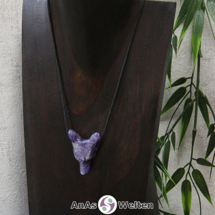 Ein Amethyst Wolf Anhänger an einem schwarzen Baumwollband, der um eine dunkle Büste gehängt wurde.