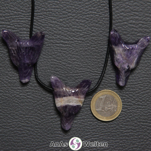 Drei Amethyst Wolf Anhänger nebeneinander. Einer befindet sich an einem schwarzen Baumwollband.