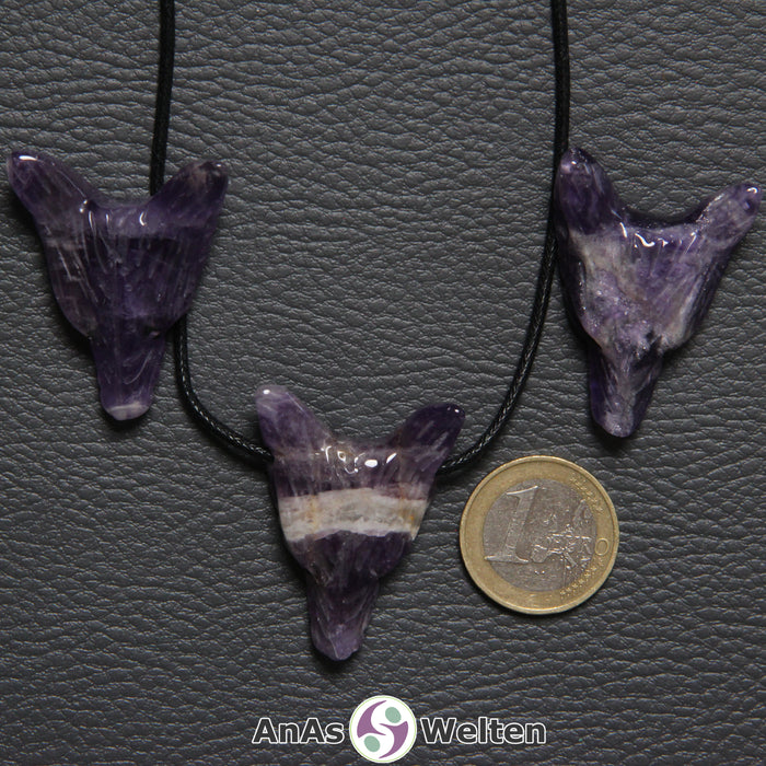 Drei Amethyst Wolf Anhänger nebeneinander. Einer befindet sich an einem schwarzen Baumwollband.