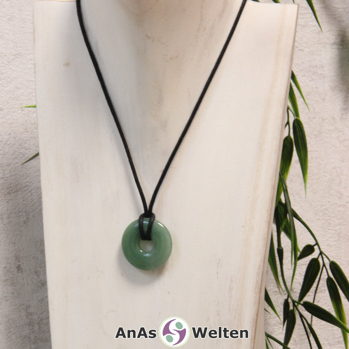 Ein Aventurin Donut als Kette an einem schwarzen gewachsten Baumwollband um eine helle Büste.